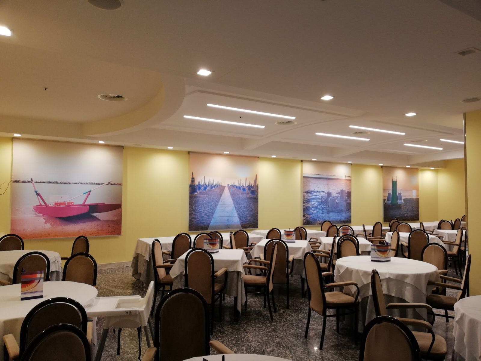 Sala da pranzo con tende a rullo stampate con immagini della spiaggia