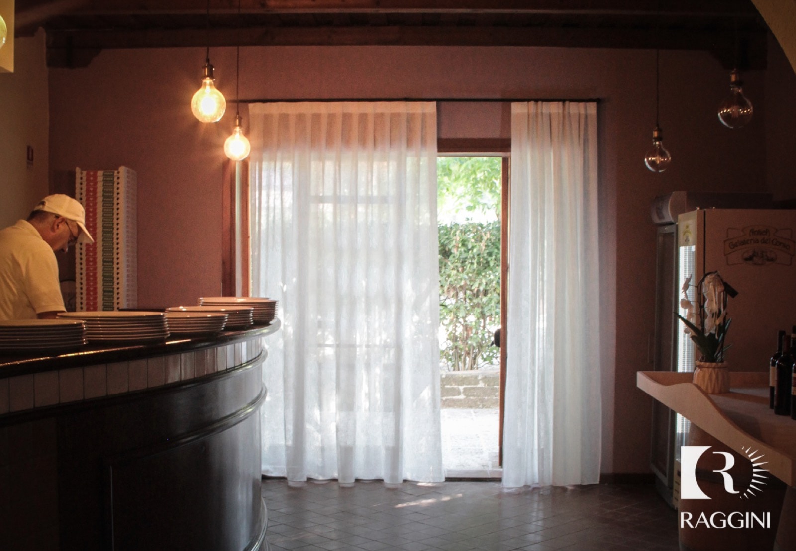 Sala del Ristorante La Vecchia Fonte con tende in lino arricciate davanti alle vetrate
