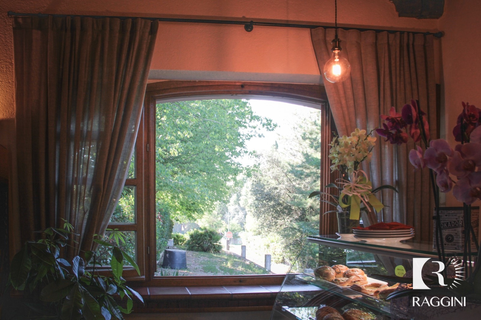 Tenda in lino raccolta davanti a una finestra aperta sul giardino