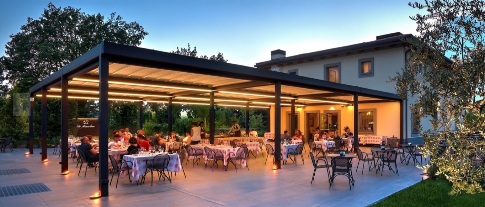 Dehors del Ristorante Le Marzoline illuminato al tramonto sotto una grande pergola