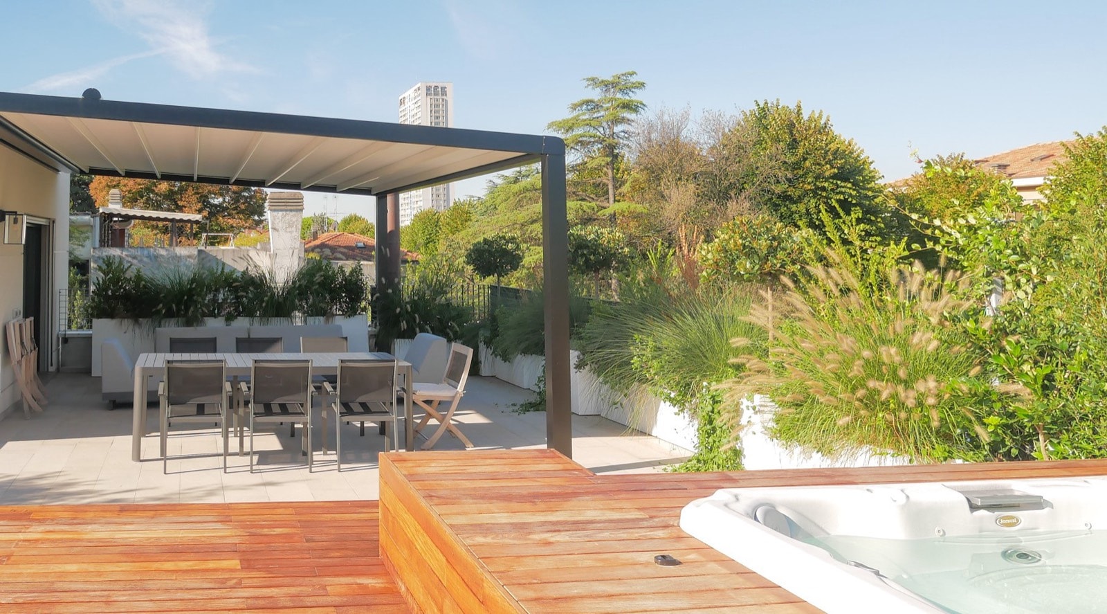 Pergola addossata marrone con zona pranzo e mini piscina idromassaggio incassata nella pedana in legno