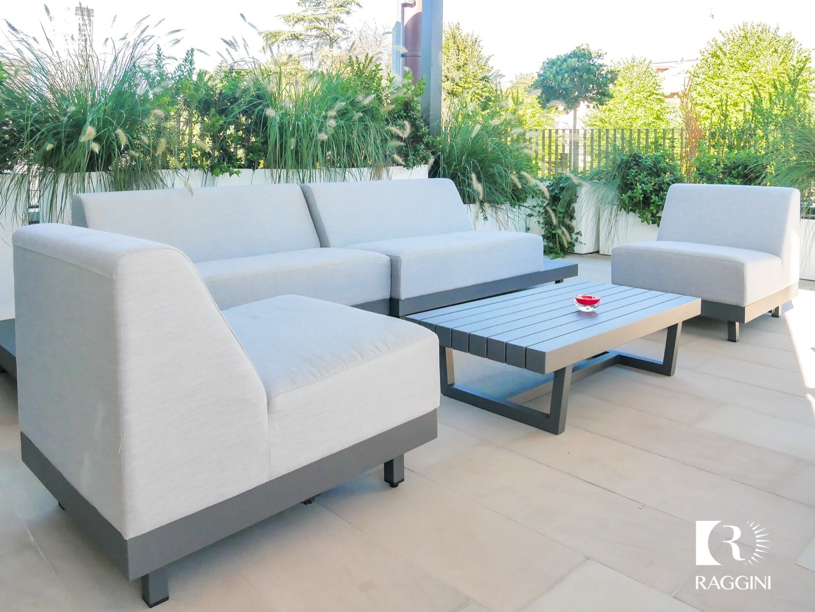 Divano modulare bianco e tavolino sotto una pergola, fra le fioriere
