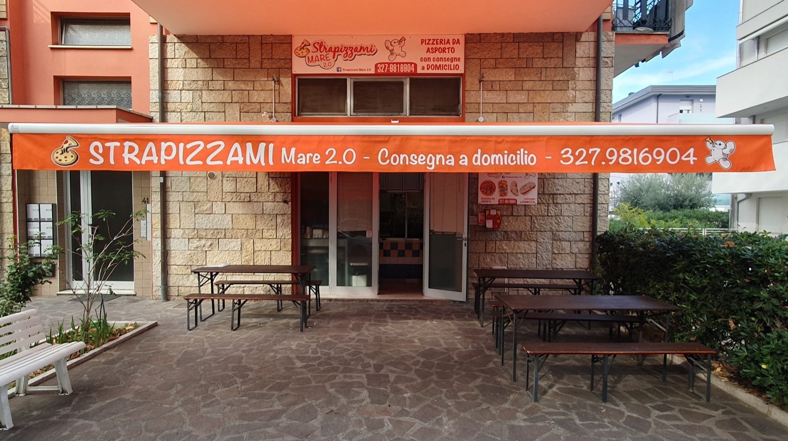 Tenda a bracci arancione con la scritta Strapizzami sopra il dehors della pizzeria