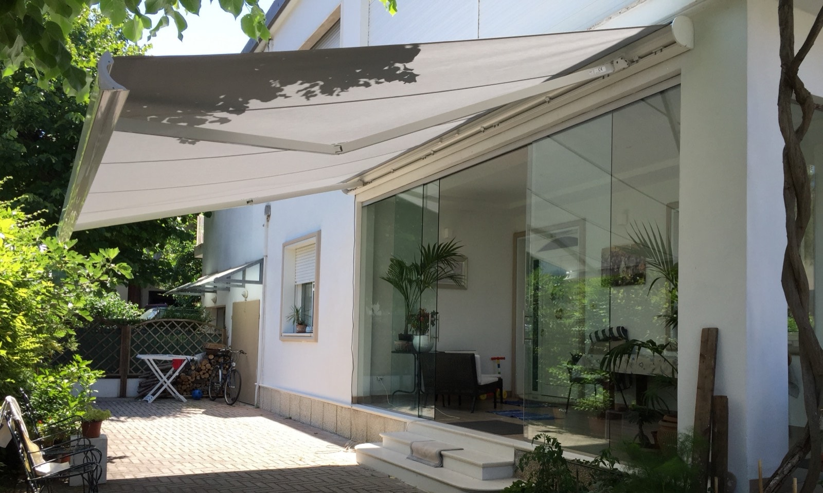 Grande tenda a bracci chiara aperta sulla vetrata di una casa