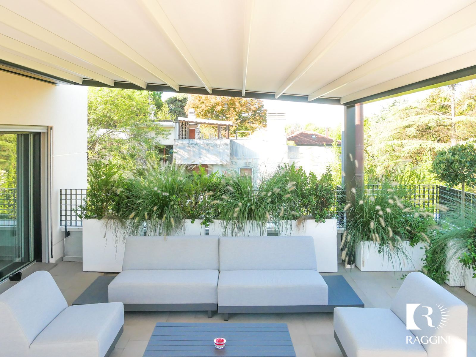 Salotto e zona pranzo sotto una pergola addossata marrone, circondati dal verde