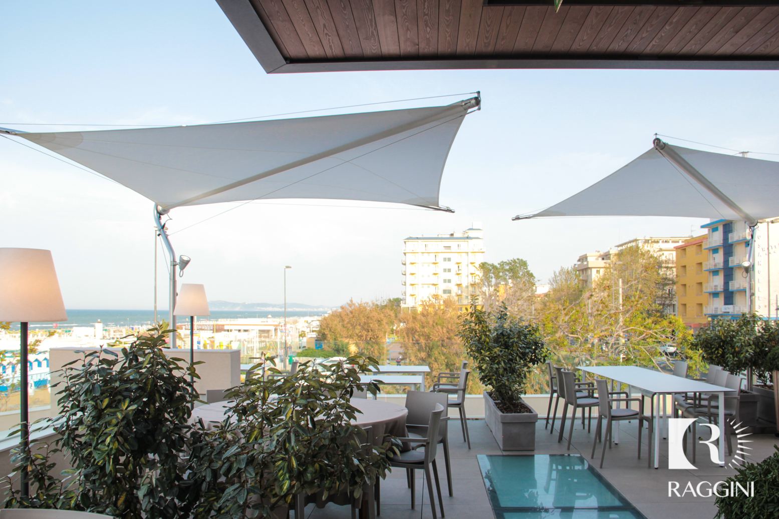 Vele ombreggianti a un palo sopra la terrazza sul mare di un ristorante